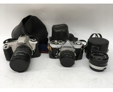 A collection of cameras and accessories including an Olympus and canon SLR together with various lenses and a light meter.