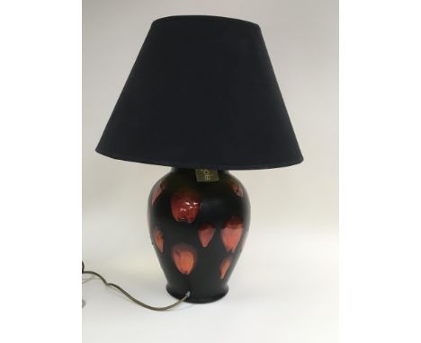 A similar and large Poole pottery lamp of baluster form with orange and red painted decoration on a black ground together wit