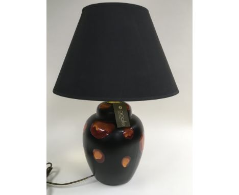 A Poole pottery lamp of baluster formwith orange and red painted decoration on a black ground together with original black la