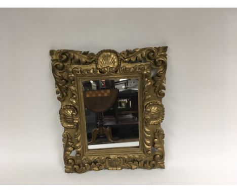 A 19th century giltwood mirror with a shell raised motif and a pierced scroll decoration. Approximately 44cm x 53cm