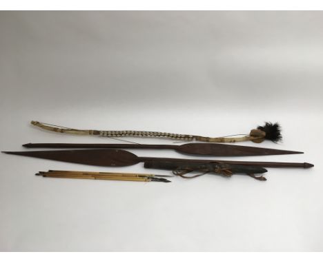 A collection of tribal items including two spears and a bow and arrows.