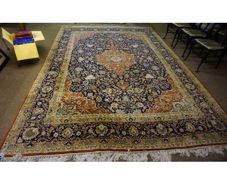 A Large Persian Carpet, Decorated with a large floral medallion, with further floral motifs on a blue and red ground, 355cm x