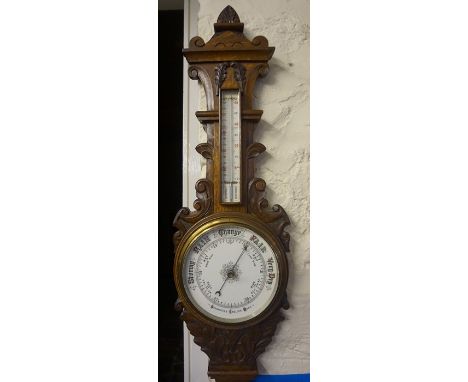 An Edwardian Carved Oak Wheel Barometer, Having a thermometer gauge above enamel dial, 88cm high