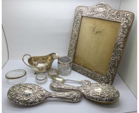 A silver photograph frame, a/f, a silver sauceboat, a/f, 110g, two silver backed brushes, a silver topped jar, a silver pill 