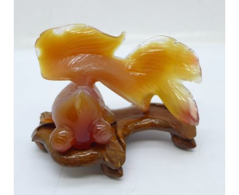 A carved jade shubunkin on a wooden stand 