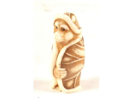 A Japanese ivory netsuke of a standing monkey in gown, signed