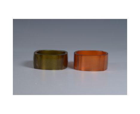 This pair of vintage Lucite bangles features bold, geometric designs with a modern flair. One bangle is a rich olive green, w