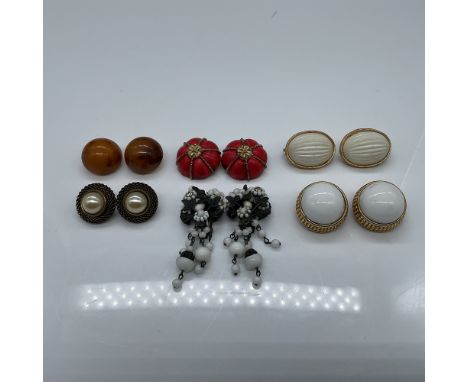 A curated collection of six pairs of vintage designer clip-on earrings featuring various materials and iconic designs. Makers