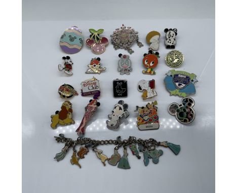 A 21-piece collection of Disney-themed pins and a charm bracelet. The lot includes a variety of enamel pins featuring beloved