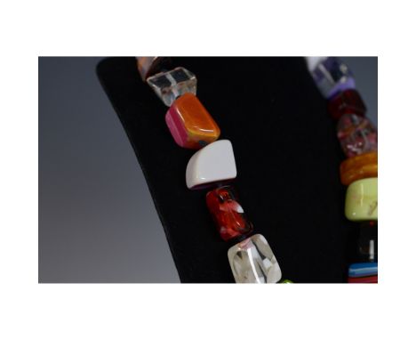 This striking necklace showcases chunky glass beads in an assortment of vibrant colors and shapes, including squares, rectang