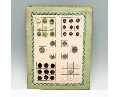 A vintage collection of assorted buttons mounted on a decorative card, featuring a variety of materials and designs. The butt