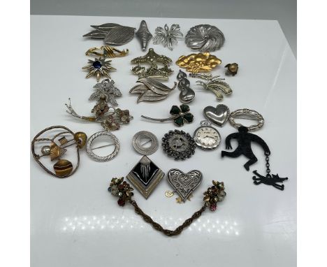 A diverse collection of vintage brooches and pins featuring a variety of designs and materials. This assortment includes flor