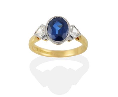 An 18 Carat Gold Sapphire and Diamond Three Stone Ring, the oval mixed cut sapphire in a white milled edge rubbed over settin