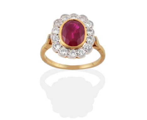 An 18 Carat Gold Ruby and Diamond Cluster Ring, the oval mixed cut ruby in a yellow rubbed over setting within a border of ro