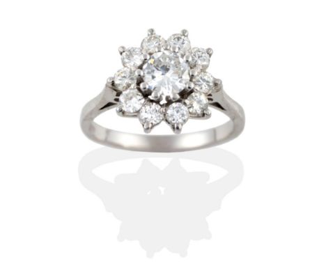 A Diamond Cluster Ring, a round brilliant cut diamond within a border of ten smaller diamonds, in white claw settings to a ta