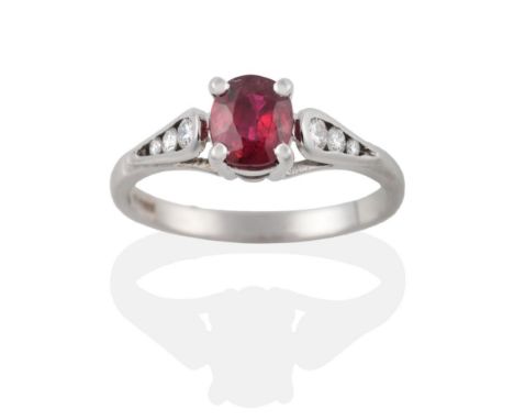 An 18 Carat White Gold Ruby and Diamond Ring, the cushion shaped ruby in a claw setting to shoulders channel set with three g