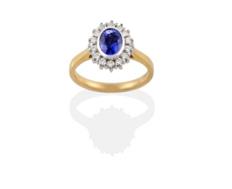 An 18 Carat Gold Sapphire and Diamond Cluster Ring, the oval mixed cut sapphire in a white rubbed over setting within a borde