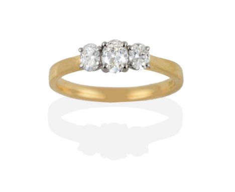 An Oval Cut Diamond Three Stone Ring, the diamonds in white claw settings on a tapered shoulder plain polished shank, total e