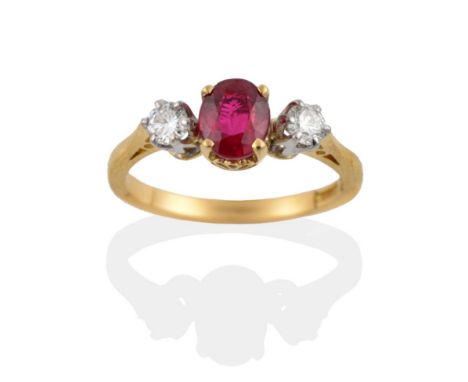 An 18 Carat Gold Ruby and Diamond Three Stone Ring, the oval mixed cut ruby in four yellow claws, flanked by a round brillian