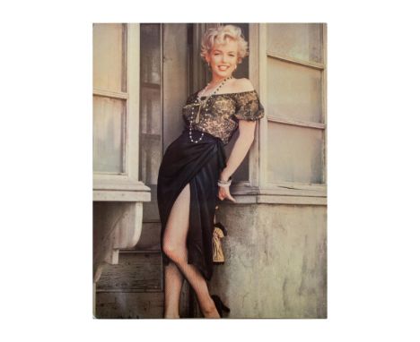 Large print on cardboard featuring Marilyn Monroe smiling in a doorway wearing a lacy top, black slit skirt, and fishnet tigh