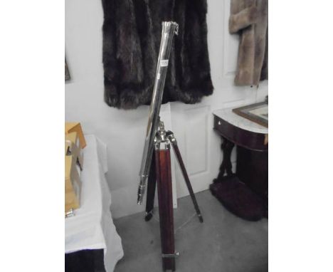 A large chrome plated telescope on a teak tripod base.