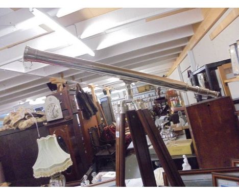 A large chrome plated telescope on a teak tripod base.