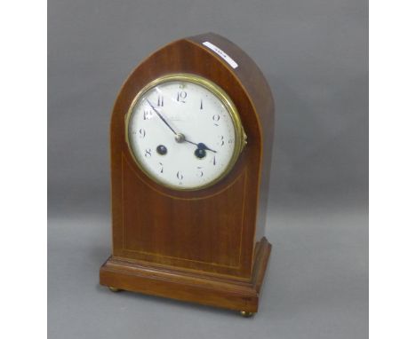 Mahogany and inlaid arched top mantle clock, the enamel dial with Arabic numerals on a rectangular base with brass bun feet, 