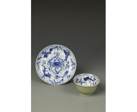 A CHINESE BLUE AND WHITE TEA BOWL AND SAUCER painted with crabs and fish, the exterior with a cafe au lait glaze, Kangxi, the