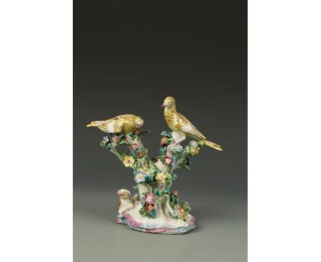 A BOW PORCELAIN ORNAMENT of two yellow birds with a nest, in a floral encrusted tree with a dog laying beside the trunk, 18th