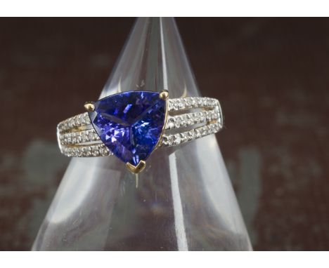 A modern tanzanite and diamond dress ring from Rocks & Co, the 18ct gold mount with pierced shoulders encrusted with brillian