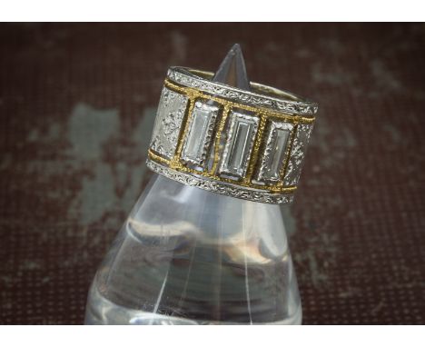 A modern 18ct white and yellow gold and three stone diamond cocktail dress ring, signed to inner rim, having textured and eng