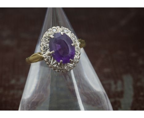 A 1970s 18ct gold and amethyst cluster dress ring, oval purple stone surrounded by brilliant cuts, 4.3g and size M 