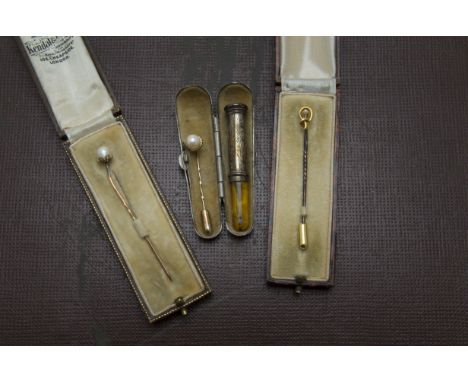 A group of three 9ct gold and pearl stick pins, each boxed, together with a silver and amber cheroot holder in a case (8) 