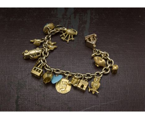 A vintage gold and yellow metal charm bracelet, oval link chain supporting multiple charms such as a Mini, a cable car, bag p