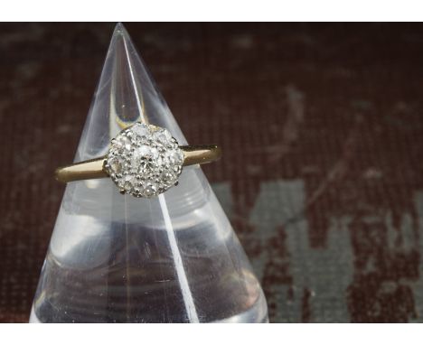 An Edwardian diamond cluster ring, the circular tablet set with old cuts in platinum claws on an 18ct gold band, 3.1g and siz