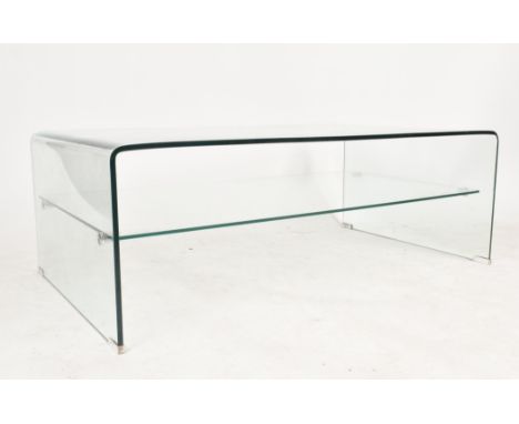 A 20th century British design curved glass two tier coffee table / low table. The table having a one piece top terminating to