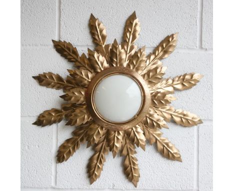 A vintage 20th century Hollywood Regency sunburst wall light sconce. The light having a central convex glass light shade with