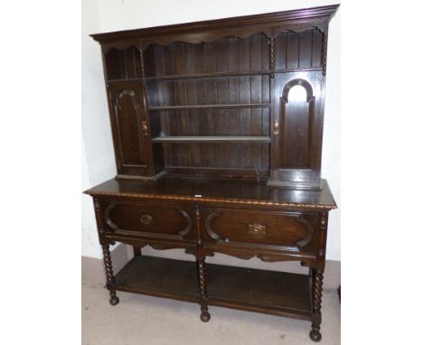 A 1930's oak Welsh dresser the raised back with cupboards and shelves over 2 drawers, and under-shelf, on barley twist legs