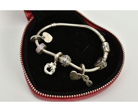 A SILVER PANDORA CHARM BRACELET, the snake chain bracelet with heart clasp signed 'Pandora' suspending six charms such as a w