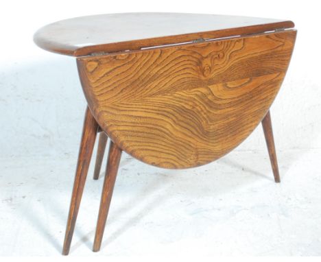 A retro 20th Century Ercol dark beech and elm round coffee table raised on tapering splayed supports. Measures 43cm x 63cm x 