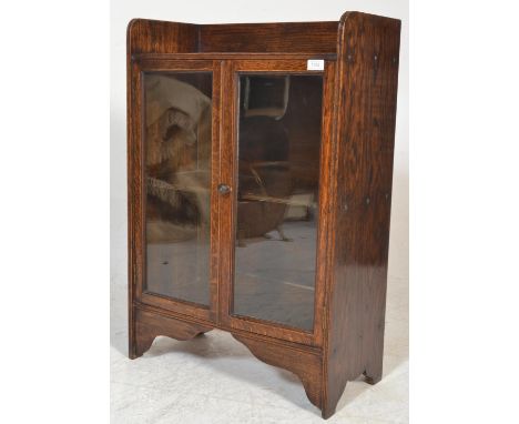 A 1940's oak bookcase cabinet having twin glass doors with gallery shelf above and central shelves behind glass doors. Measur