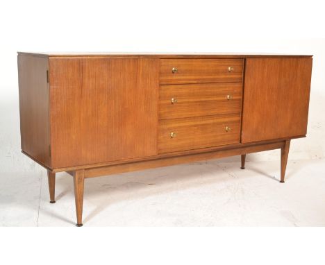 A 1970's retro vintage teak wood sidebaord credenza having a bank of three drawers flanked by two shelved cupboards, all rais