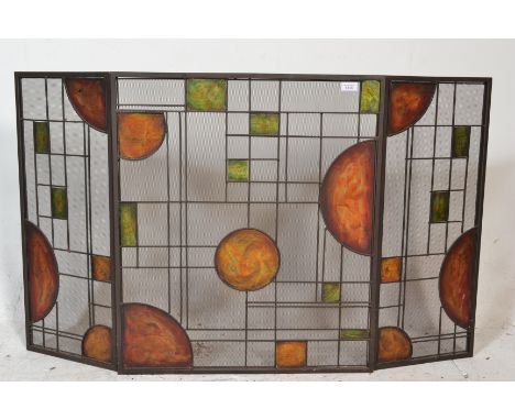 A 20th Century Art Nouveau style tri-fold fire screen of metal construction having green and orange, square and circular pane