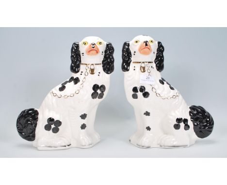 A pair of early 20th Century ceramic Wood and Sons Staffordshire fire dogs having hand painted black and gilt details. Marked
