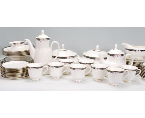 A vintage Royal Doulton Vogue Collection 'Enchantment' china dinner service, having a white ground with gilt and black border