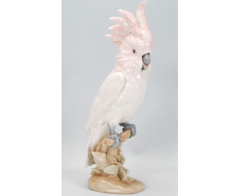 A 20th Century Royal Dux ceramic figurine in the form of a parrot / cockatoo having white and pink plumage raised on a natura