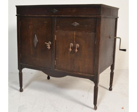 An early 20th century oak cased gramophone cabinet raised on squared legs with speaker doors to lower section, hinged top enc