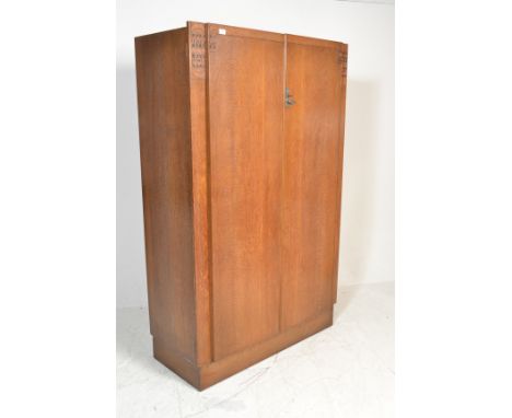 An early 20th Century Ernst Gomme for G Plan oak double wardrobe, two panel doors opening to reveal shelf to inner with twin 