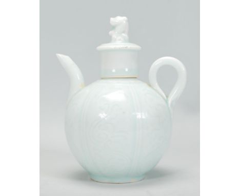 An early 20th Century Chinese teapot of small proportions finished in a light green glaze having scroll and foliate decorated