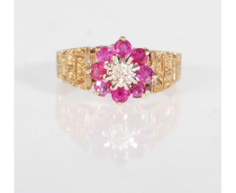 A hallmarked 9ct gold ruby and diamond ring. The ring having a central star set diamond surrounded by a halo of rubies comple